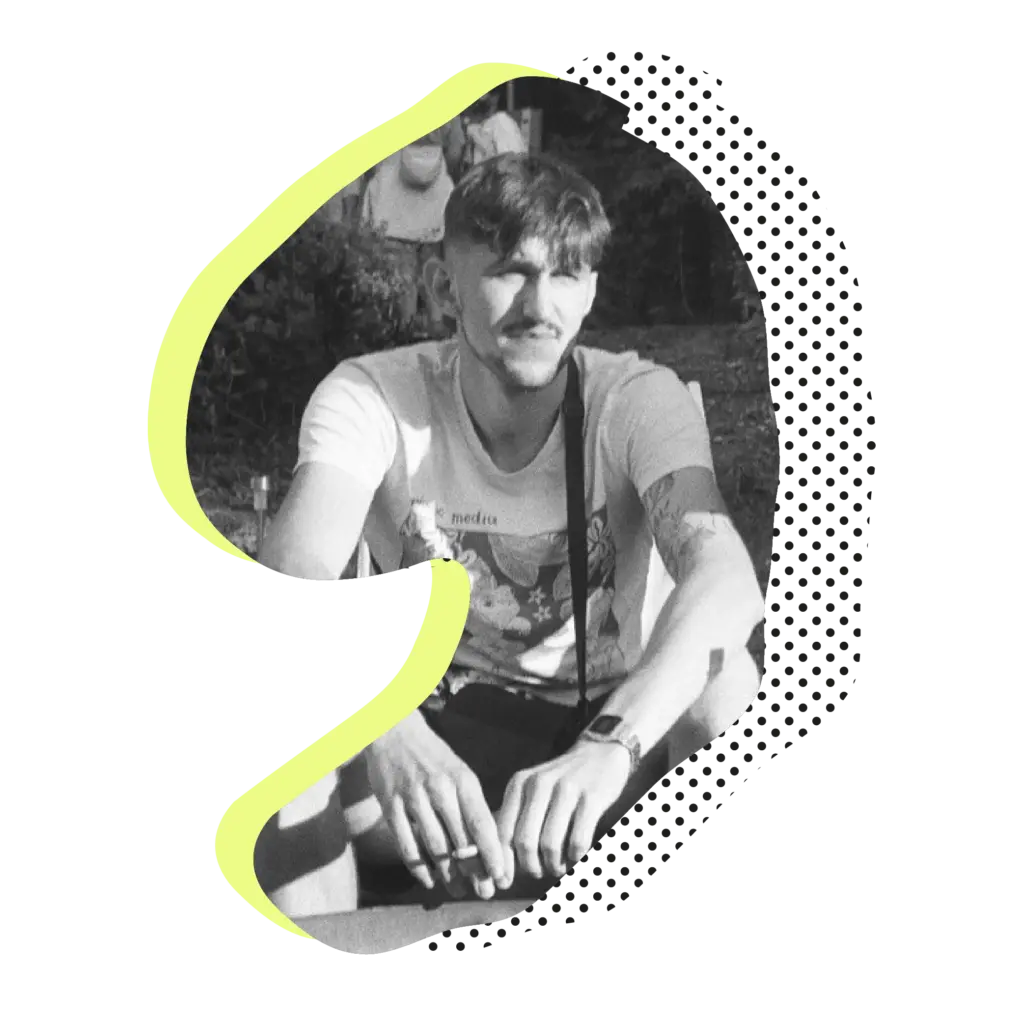 Schwarzweiß-Porträt eines tätowierten Tätowierers Niklas im Sitzen.